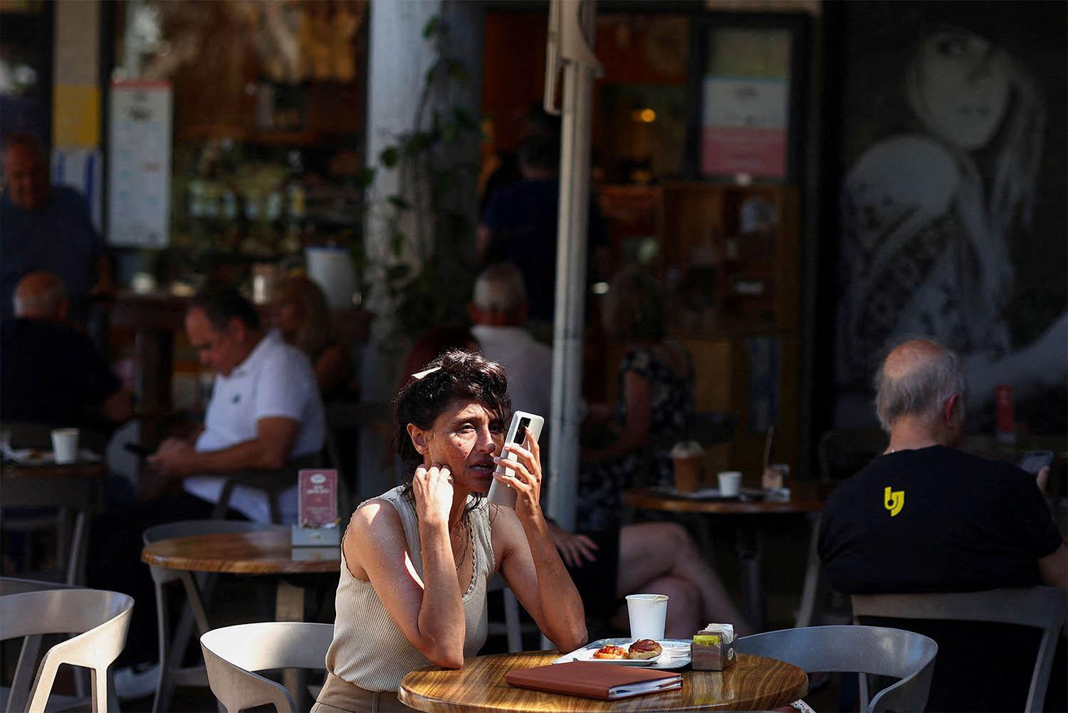 Israelis sit at a cafe, after US President Trump announced a ceasefire between Israel and Iran, in Haifa