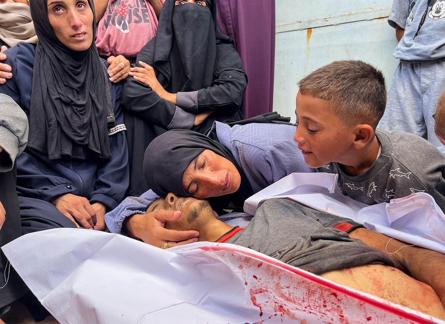 The mother of Hesham Ifsifis, who was killed in Israeli fire while seeking aid near a distribution point mourns over his body