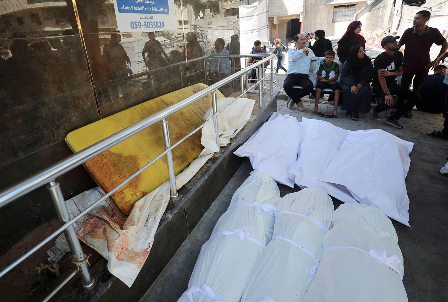 Mourners sit next to dead bodies during the funeral of Palestinians killed in an Israeli strike 