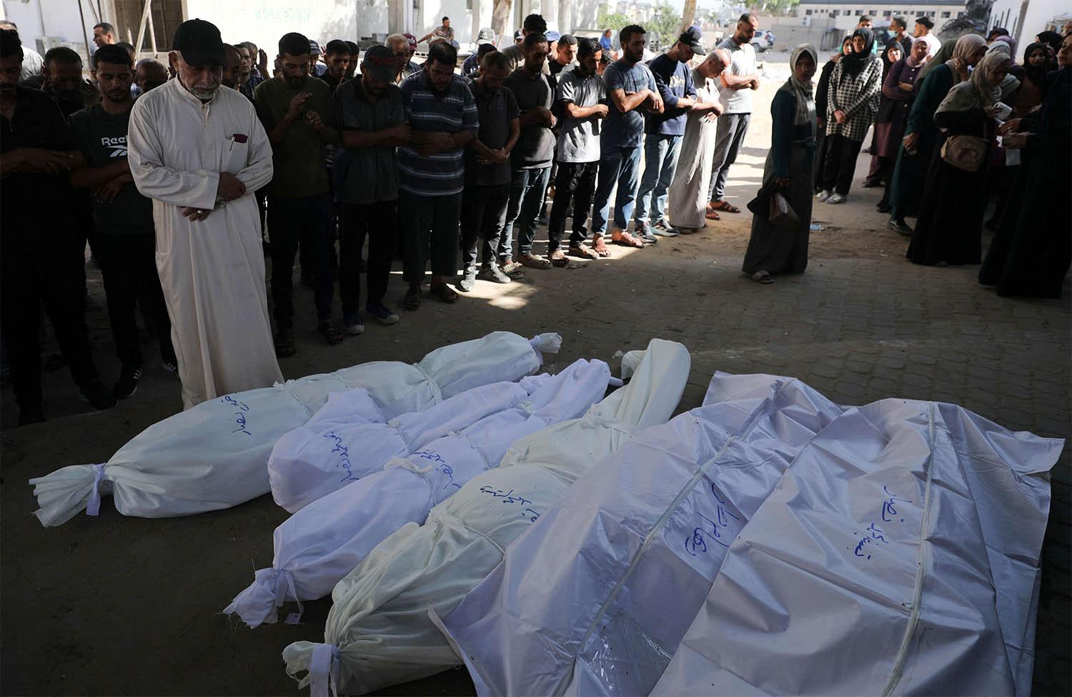 Mourners pray next to shrouded bodies during the funeral of Palestinians killed in an overnight strike on a tent in Gaza City