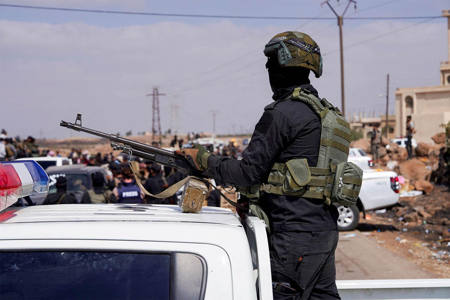 A member of Internal Security Forces holds a gun at an Internal Security Forces checkpoint in Syria
