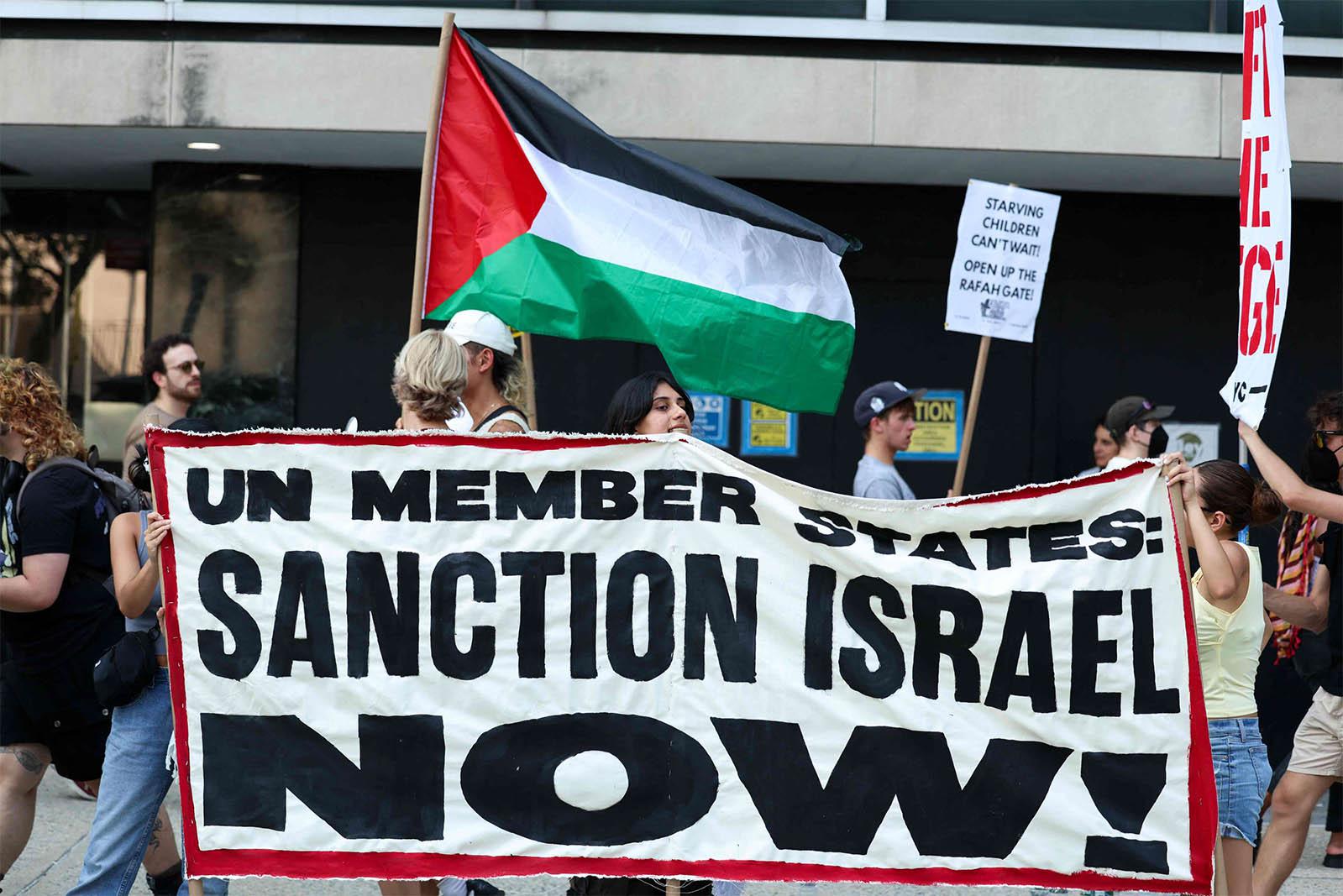 People hold a large sign as they protest outside United Nations headquarters where a UN conference on a two-state solution for Israel and the Palestinians in New York city
