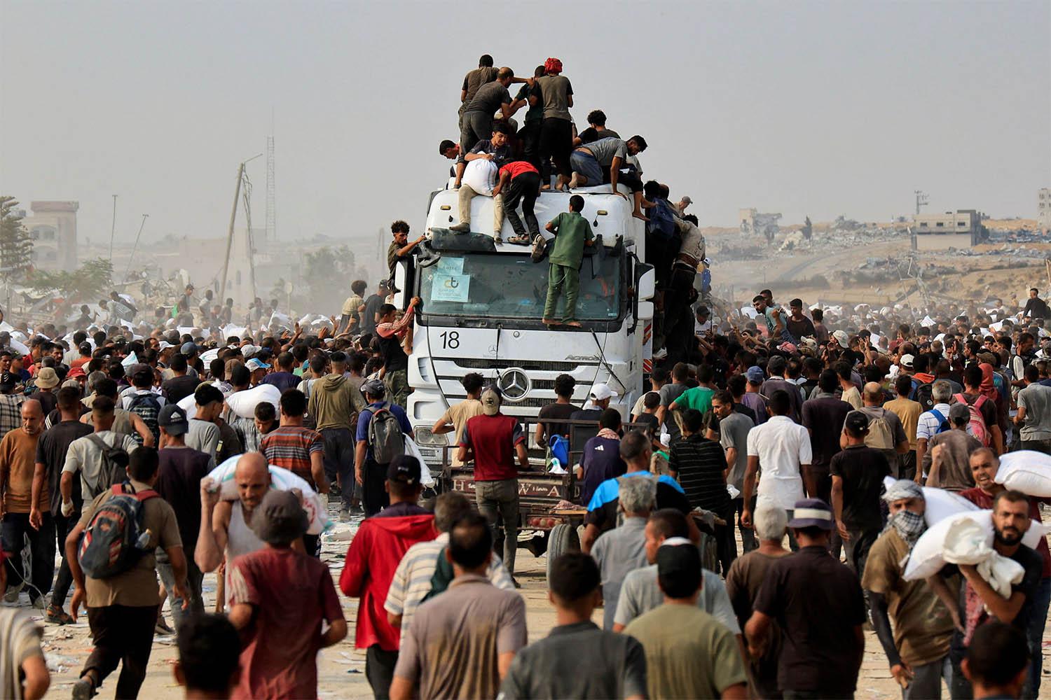 Palestinians scramble to collect aid supplies from trucks that entered through Israel, in Khan Younis