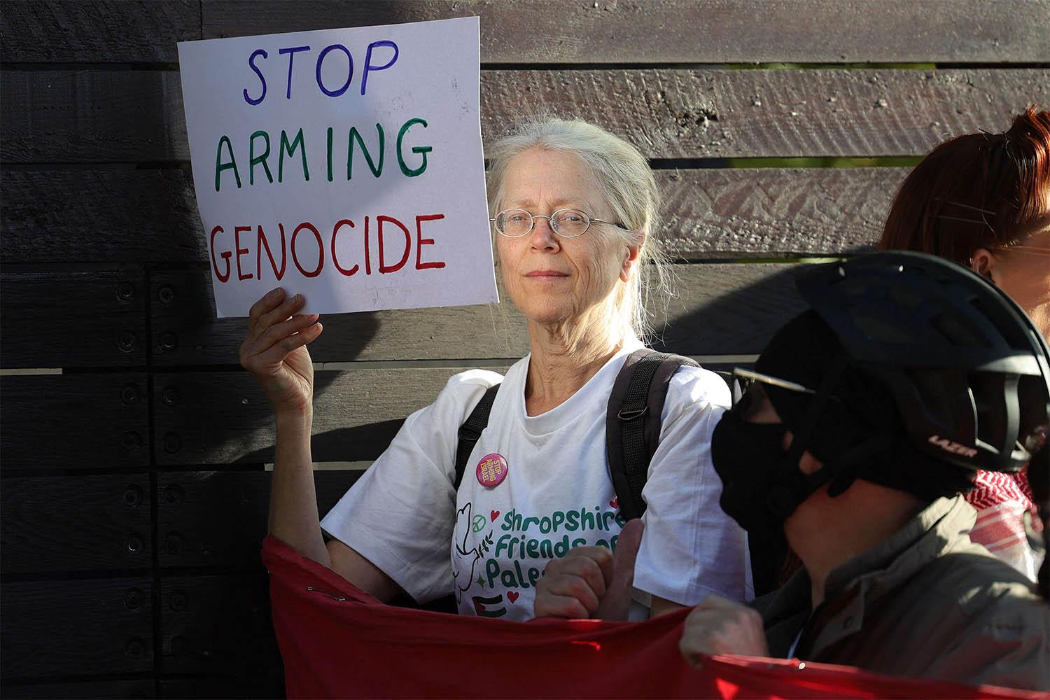 A demonstrator holds a placard reading "Stop Arming Genocide" in a protest outside the entrance to the Defence and Security Equipment International fair at the ExCeL centre in east London