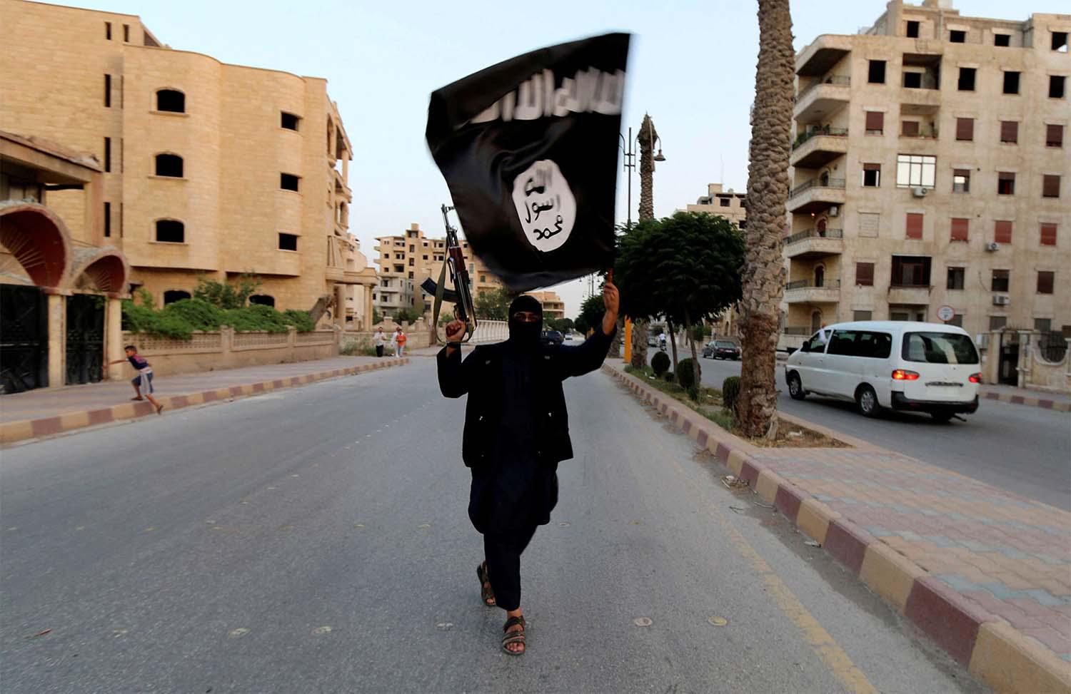 A member loyal to the Islamic State in Iraq and the Levant (ISIL) waves an ISIL flag in Raqqa, Syria June 29, 2014