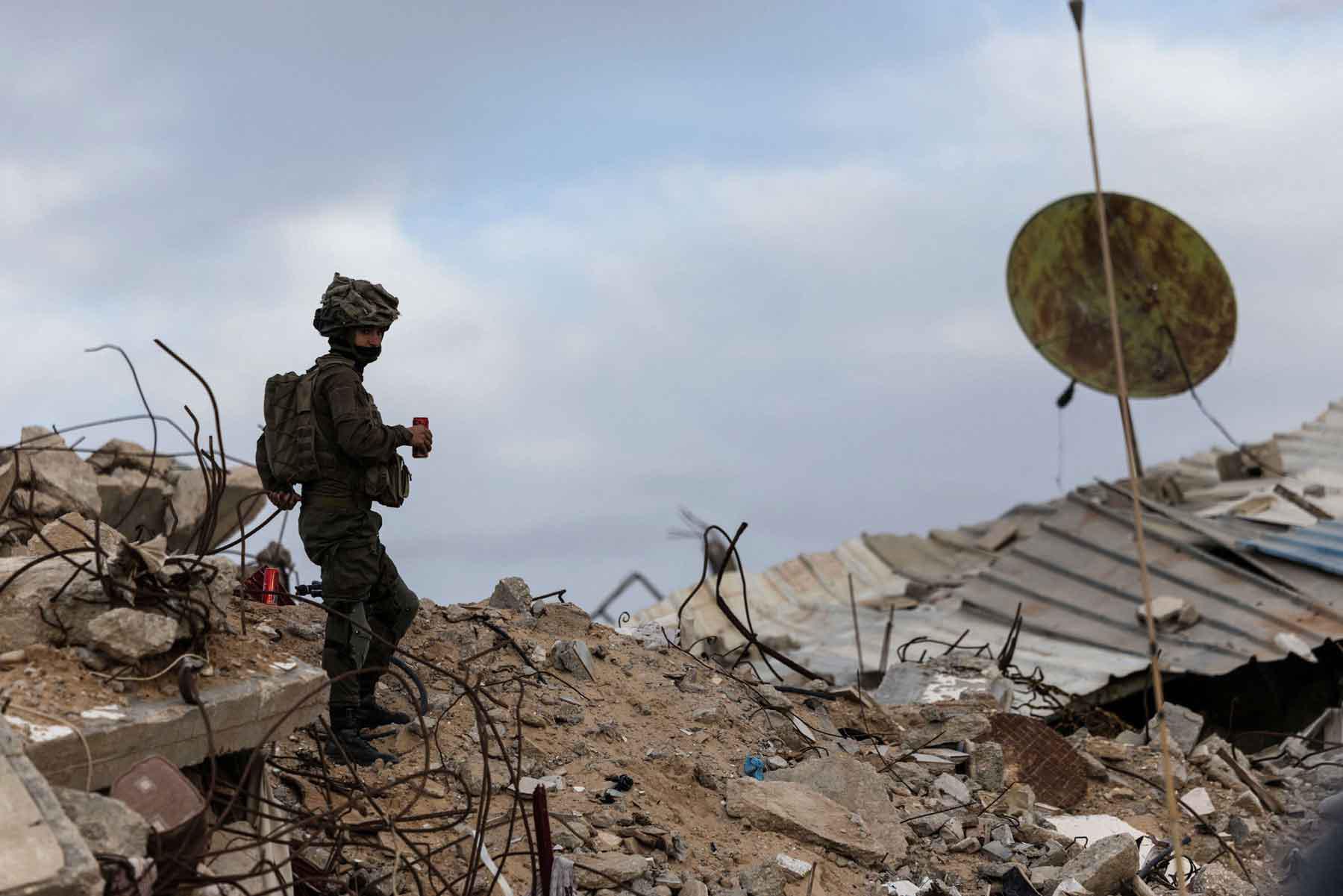 An Israeli soldier holds a drink as he stands on rubble in Rafah in the southern Gaza Strip, December 8, 2025. 