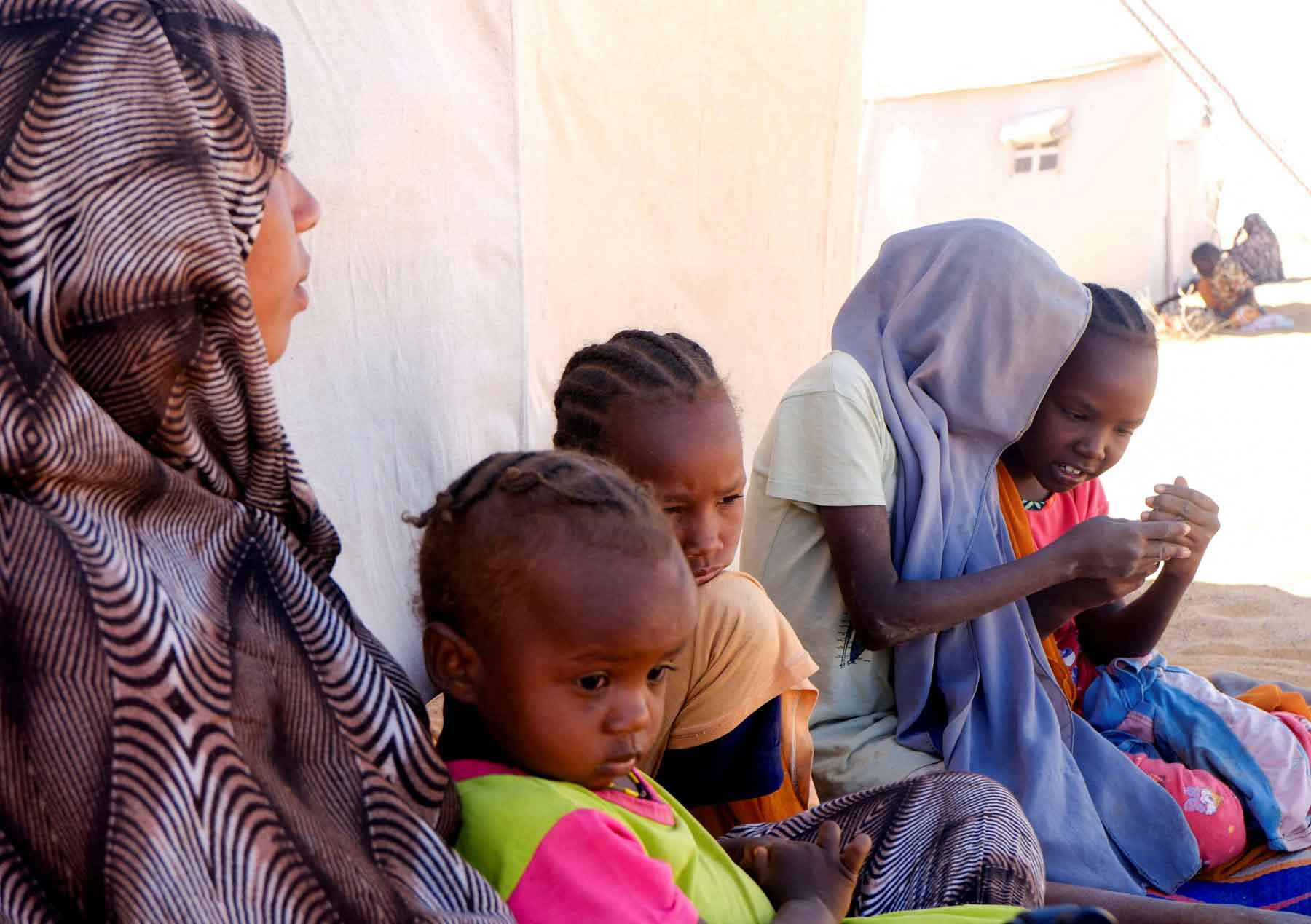 A displaced mother sits with her children in front of their tent, in a displacement camp in Al-Dabbah, Sudan, November 15, 2025. 