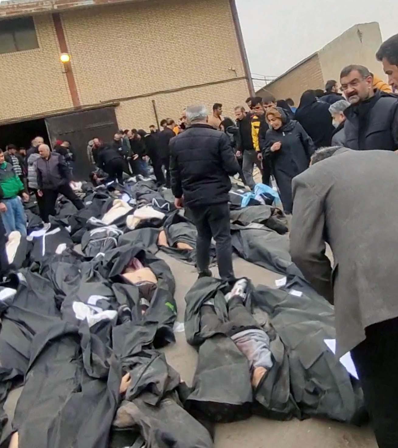 People gather next to bodies lying in body bags outside Kahrizak Forensic Medical Centre in Tehran